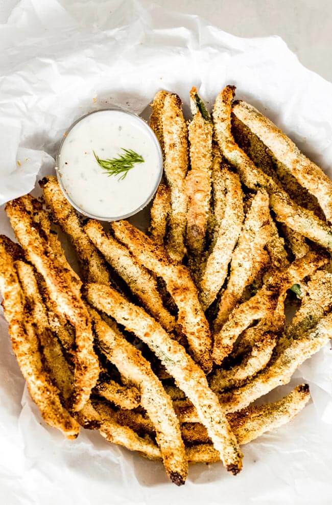 Breaded air fryer green beans on a plate with ranch sauce