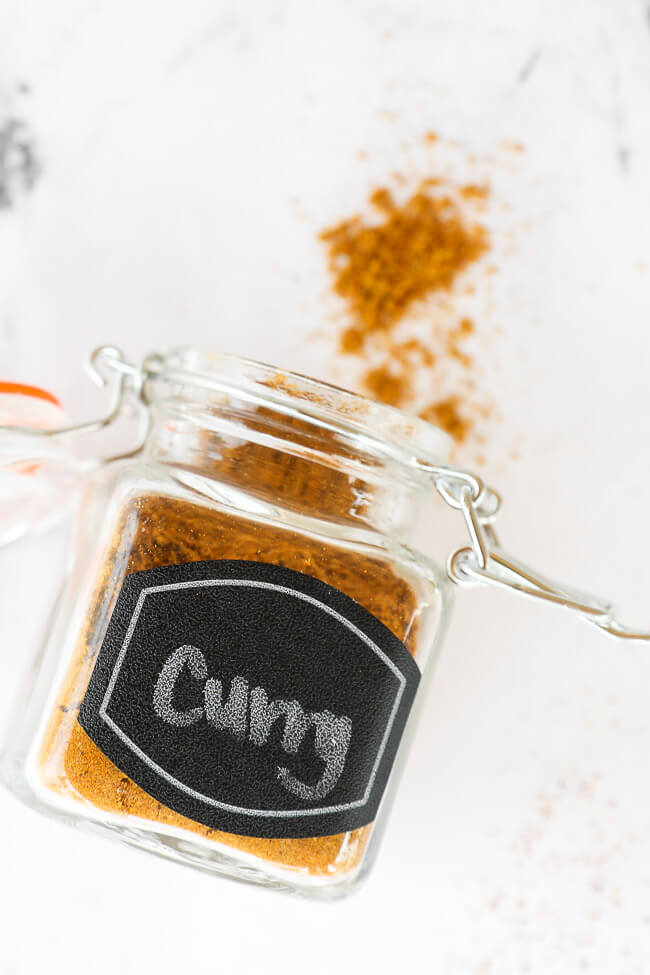 Curry seasoning in a jar with label laying on counter with some spilling out of the top