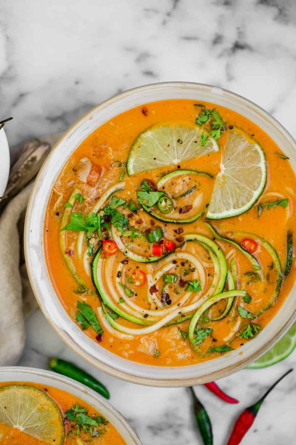 Bowl of Thai soup with zoodles limes and chopped parsley