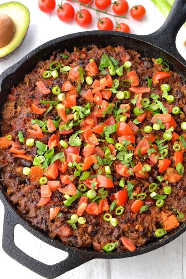 Beef and cauliflower rice mexican casserole in cast iron pan with tomato and green onion toppings - healthy casseroles