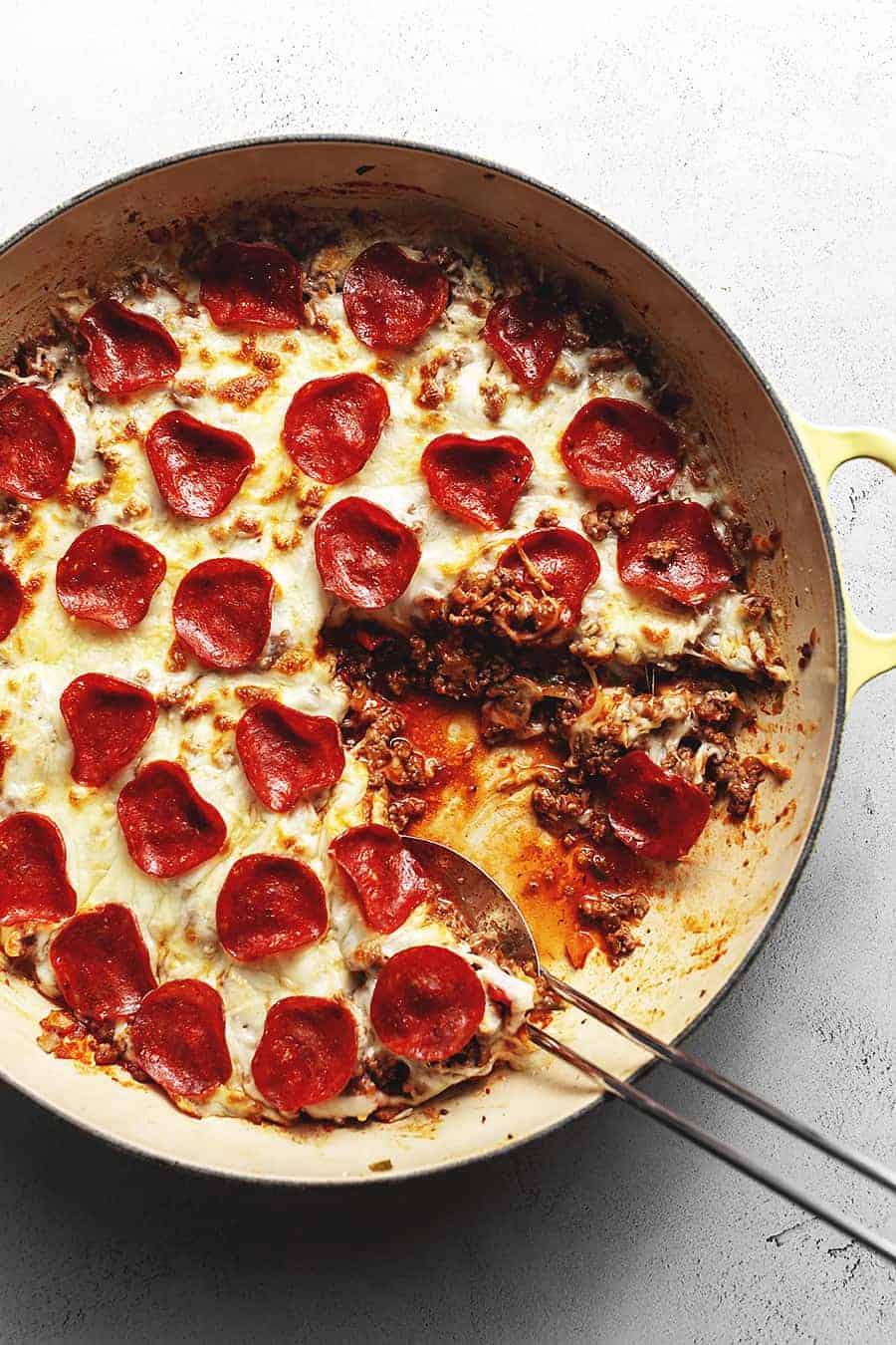 Keto meat lovers pizza casserole in a skillet topped with cheese and pepperoni