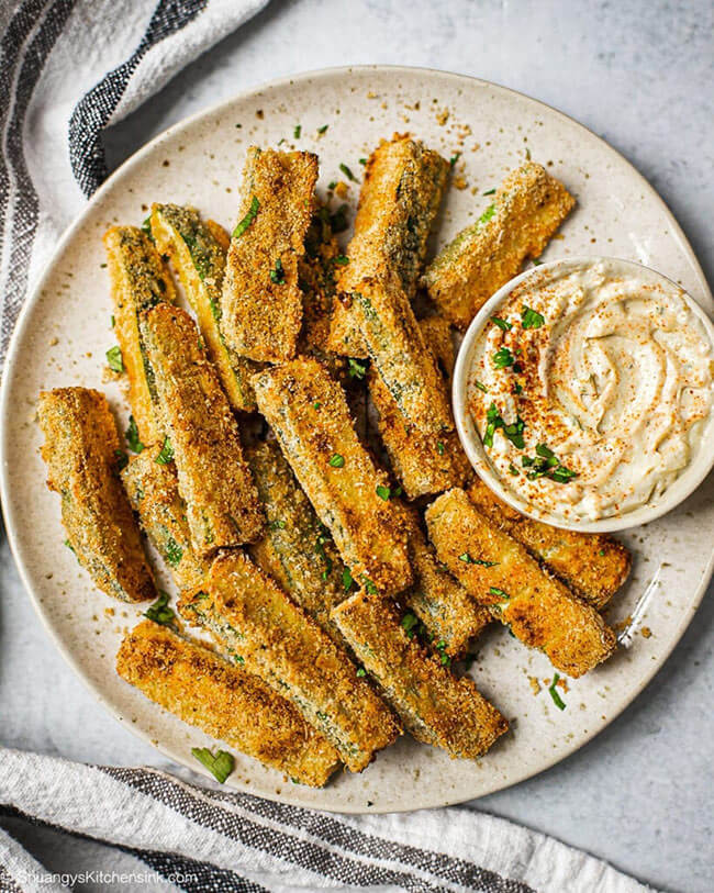 Zucchini fries on a plate with sauce in a ramekin