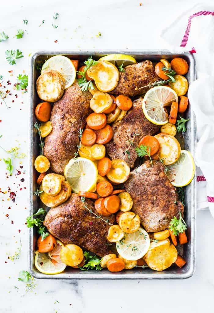 Sheet pan filled with pork chops, citrus slices and sliced carrots