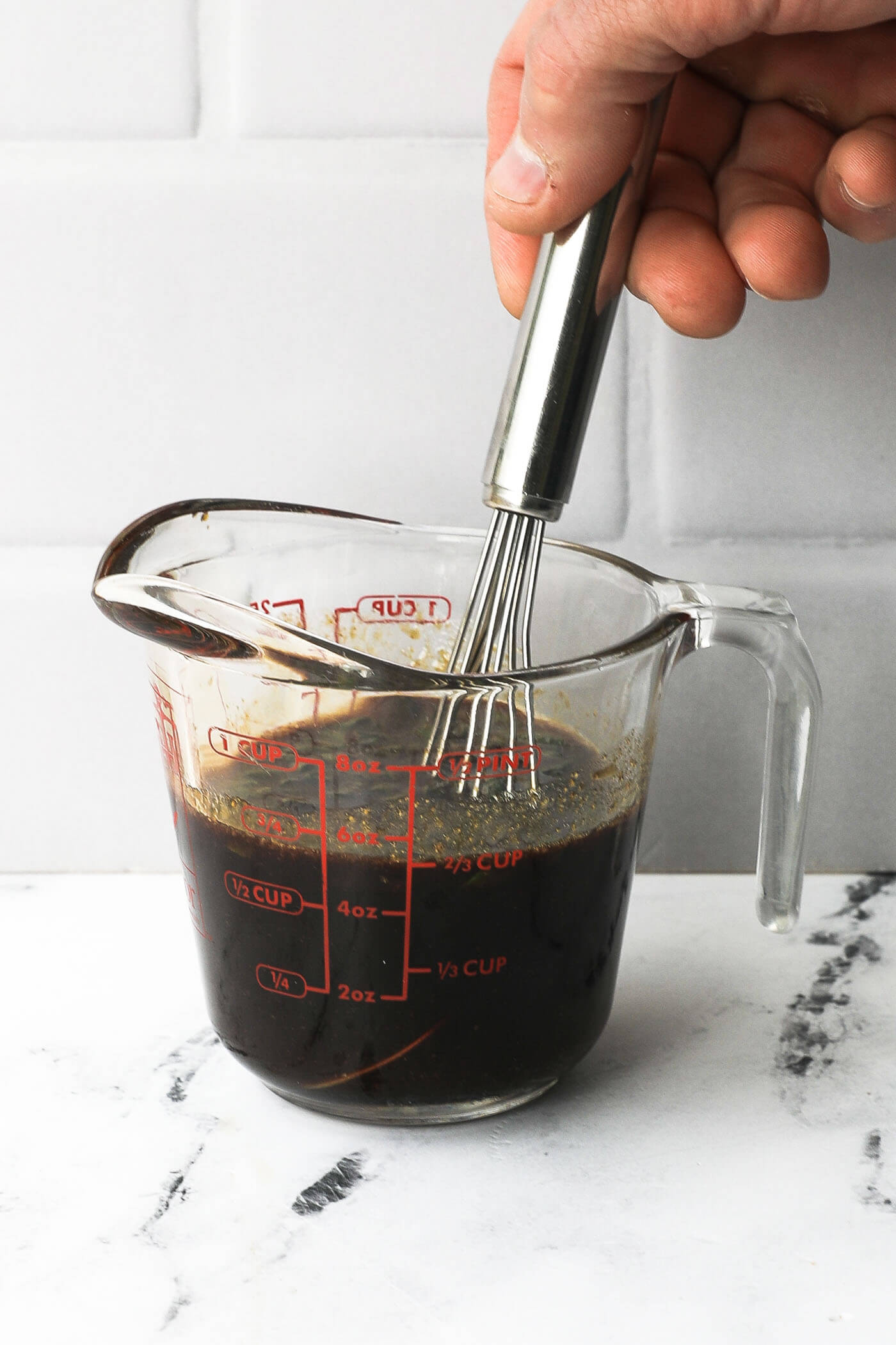 Stirring teriyaki marinade ingredients together in a glass measuring cup.