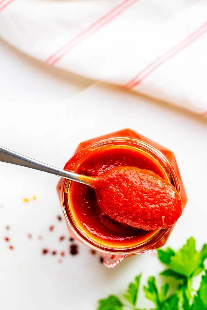 Overhead shot of jar of homemade keto ketchup with a spoonful sitting on top 