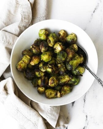 Bowl of cooked air fryer brussel sprouts from frozen with a balsamic vinegar drizzle.