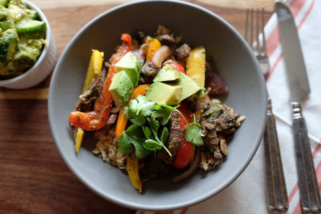 These Paleo steak fajita bowls are so much fun! Served over cauliflower rice, the delicious marinated steak and bell peppers are so EASY to make! Paleo, Gluten-Free and Dairy-Free. | realsimplegood.com