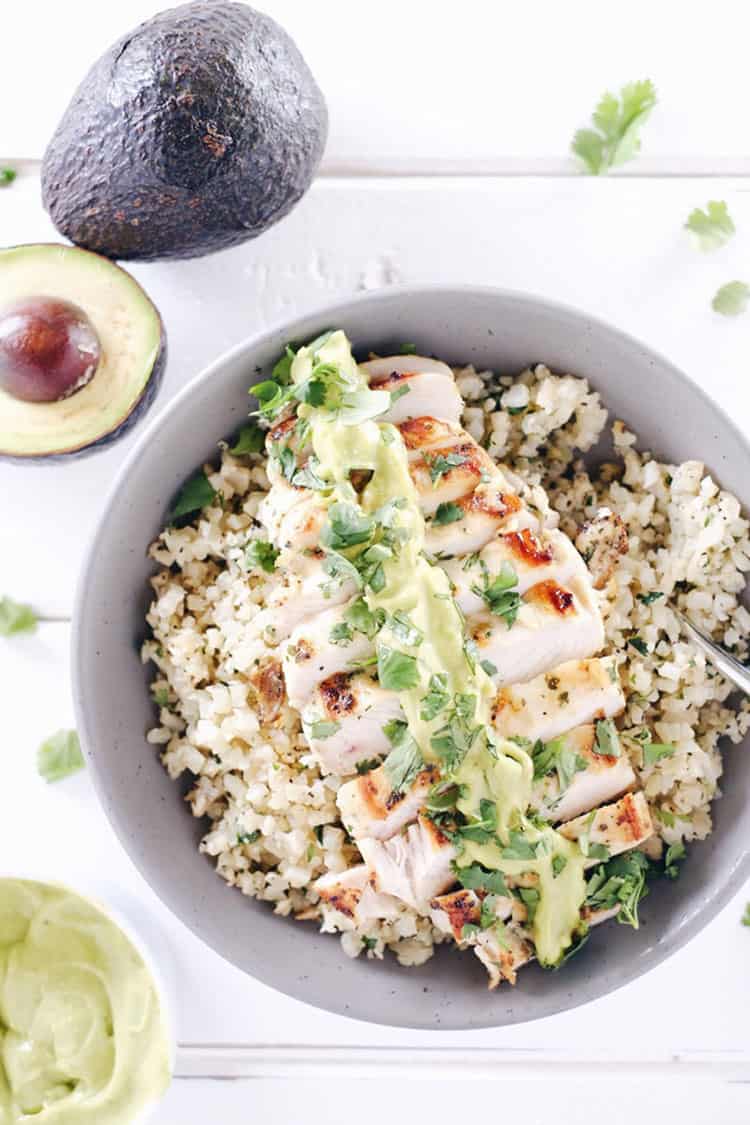This cilantro lime chicken bowl is everything you need for a EASY Paleo + Whole 30 meal. Marinated chicken over cauliflower rice with a creamy avocado sauce! Paleo, Whole30, Gluten-Free and Dairy-Free. | realsimplegood.com
