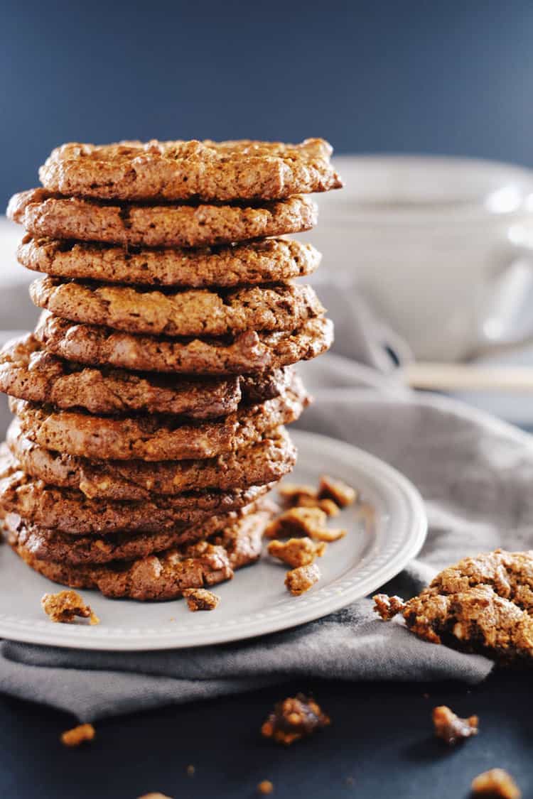 Large stack of cookies on a plate with crumbs around