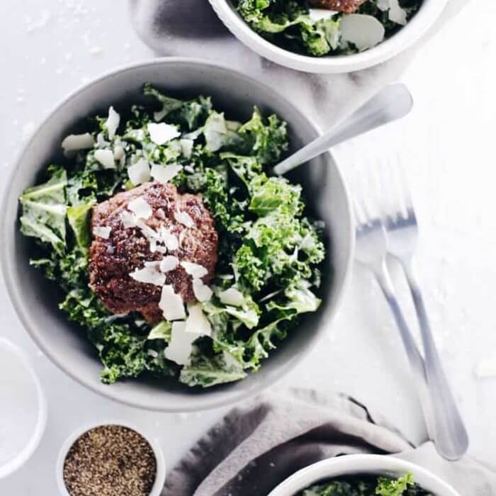 3 bowls of caesar salads with burgers and parmesan cheese on top