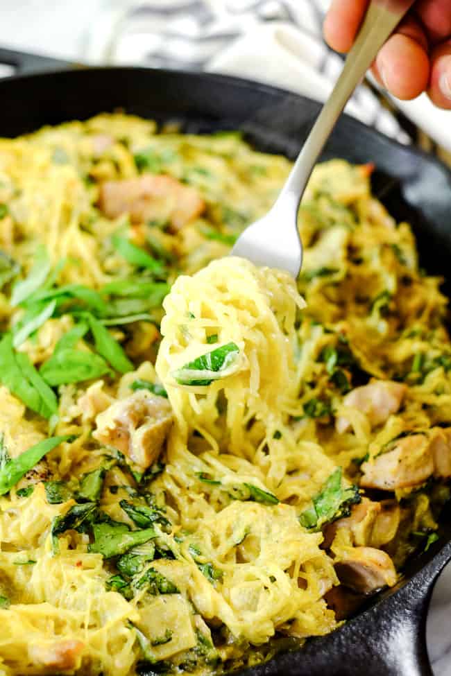 Creamy chicken casserole in cast iron skillet with fork full of noodles coming out of dish - healthy casseroles