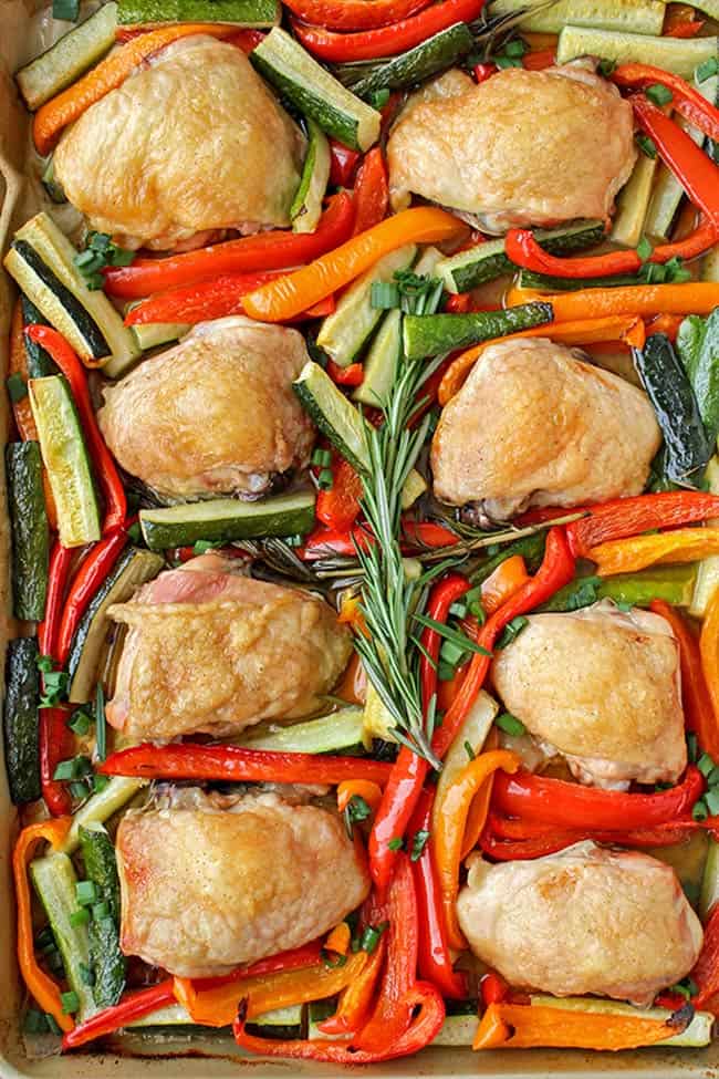 Sheet pan filled with chicken thighs, zucchini and peppers