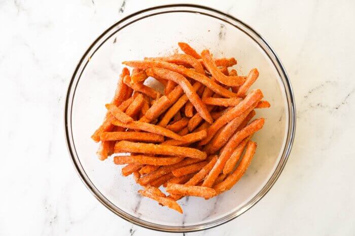 Frozen sweet potato fries in a bowl tossed with seasoning