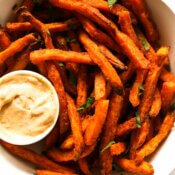 Crispy cooked sweet potato fries in a bowl with dipping sauce on side