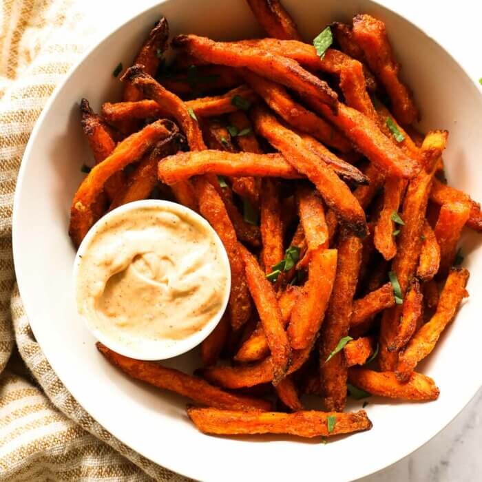 Overhead image of air fryer sweet potato fries from frozen in a bowl with dipping sauce