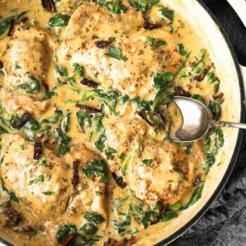 Overhead shot of dairy free creamy tuscan chicken with spinach and sun dried tomatoes and spoon coming out