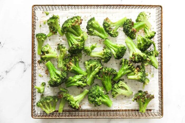 Cooked broccoli florets in air fryer basket