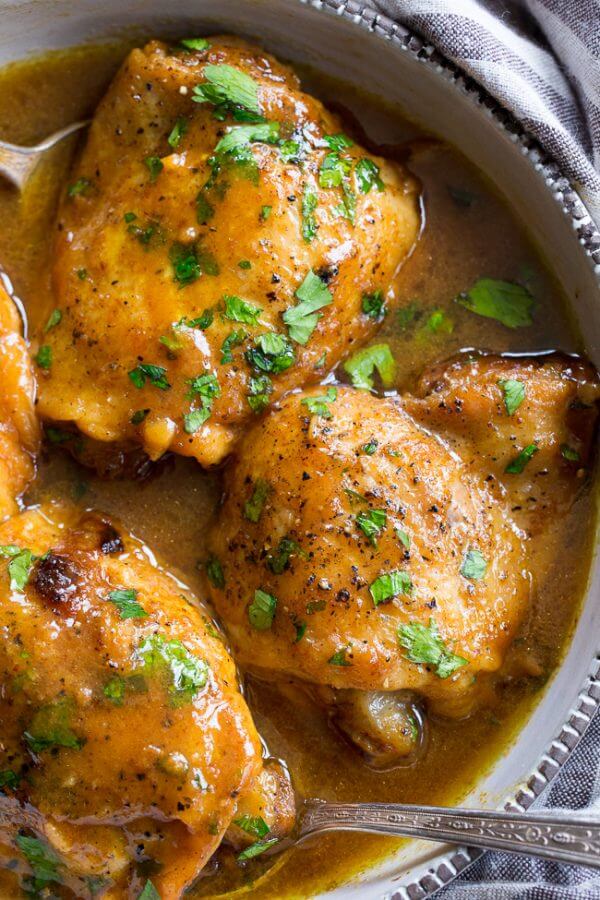 Close up of honey mustard chicken in dish with sauce and spoons