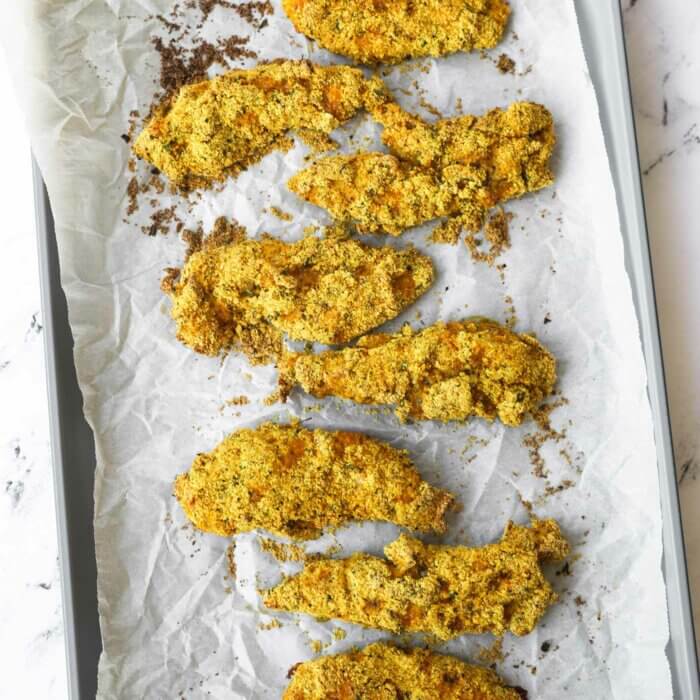 Overhead image of baked almond flour chicken tenders on a sheet pan