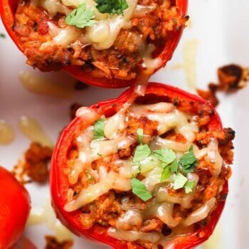 Close up overhead image of a stuffed bell pepper with melty cheese on top and chopped parsley.