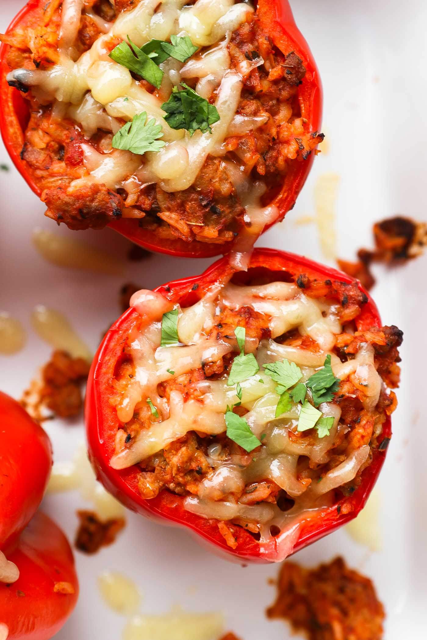 Close up overhead image of a stuffed bell pepper with melty cheese on top and chopped parsley. 