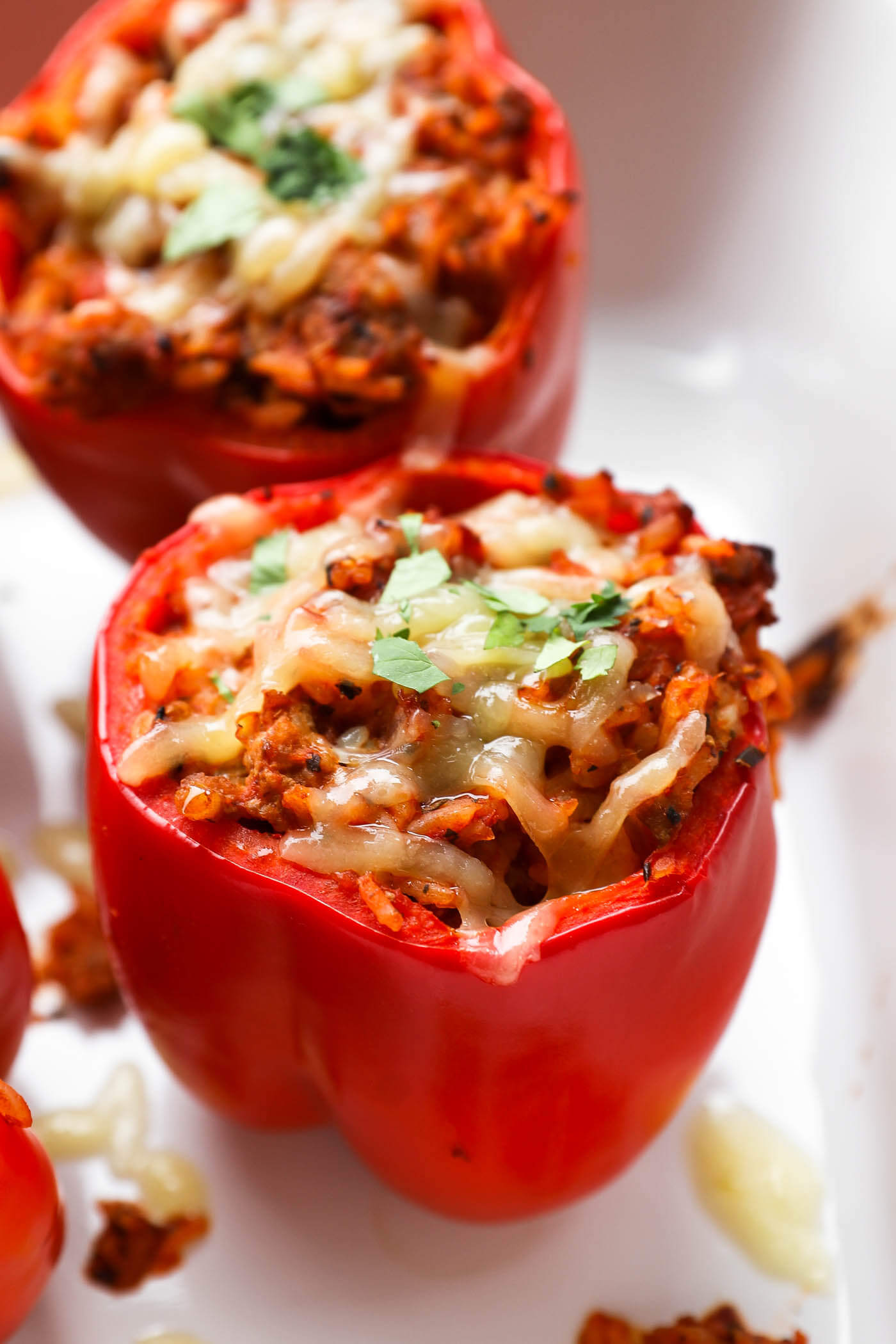 Angled image of a stuffed pepper with melty cheese and chopped parsley on top. 