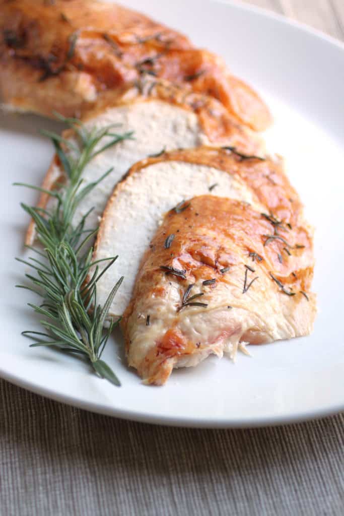 Sliced turkey with rosemary on a white plate