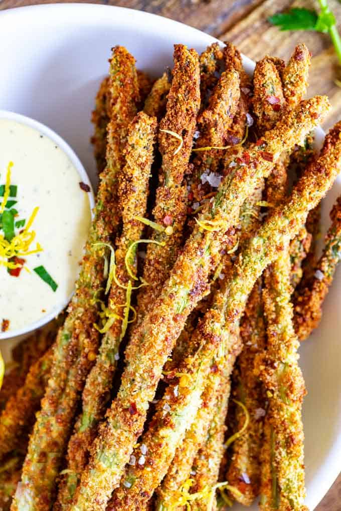 A plate of cheesy asparagus fries with sauce