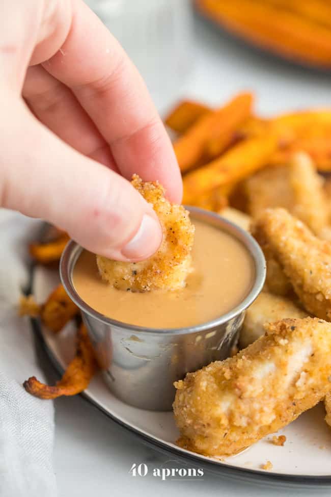 chicken nuggets with hand holding nugget dipping in sauce