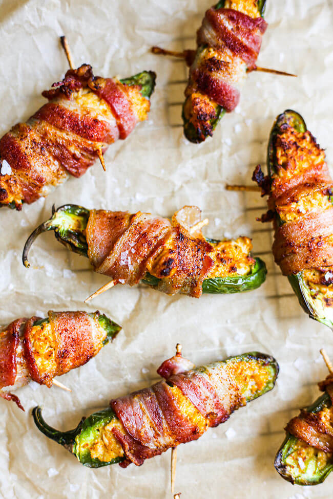 Stuffed jalapeno peppers wrapped in bacon on parchment paper