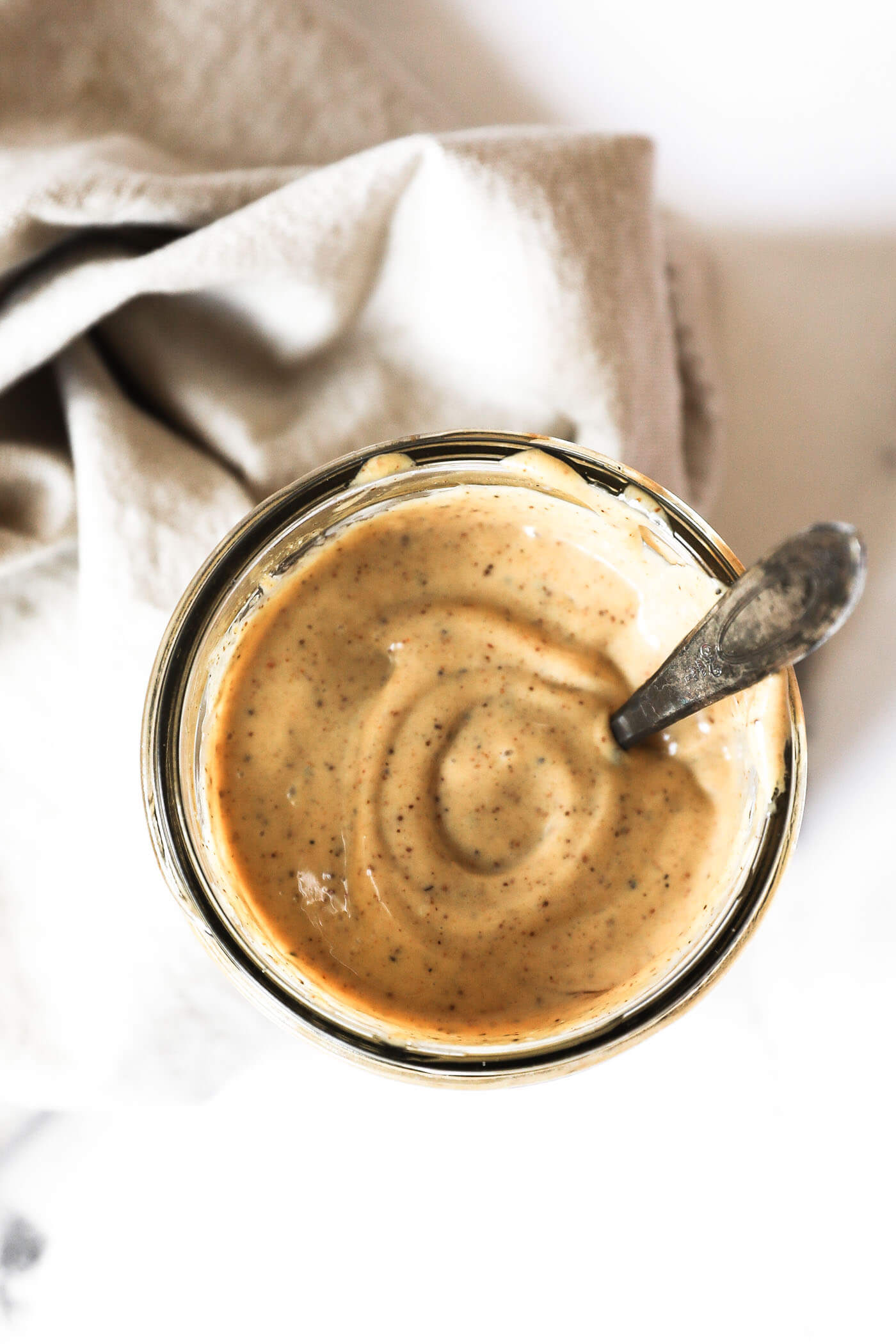 Overhead image of homemade aioli sauce in a mason jar with a spoon in the jar.