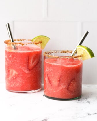 Two glasses of frozen strawberry daiquiri mocktails with brown sugar rim, lime wedge and straws