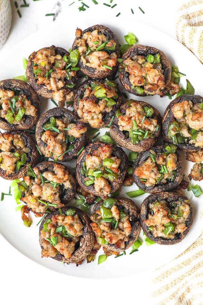 Overhead image of a plate full of sausage stuffed mushrooms.