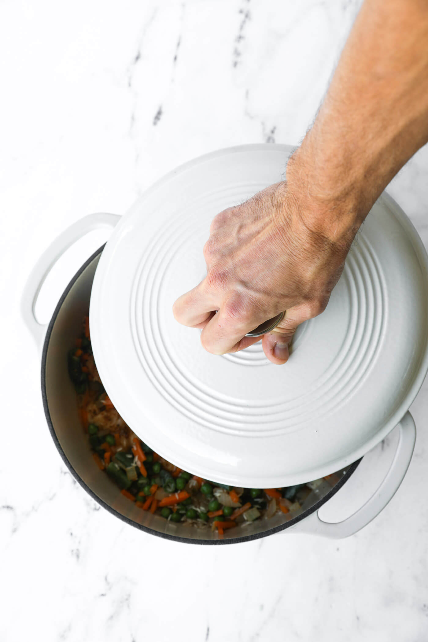 Hand placing lid on dutch oven.