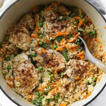 Overhead image of dutch oven chicken and rice with peas, onions and carrots.