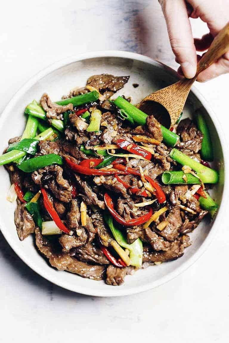 Mongolian beef on plate with spoon and hand