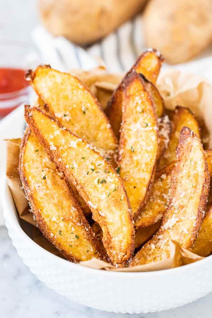 Air fryer potato wedges in a bowl with a sprinkle of parmesan cheese