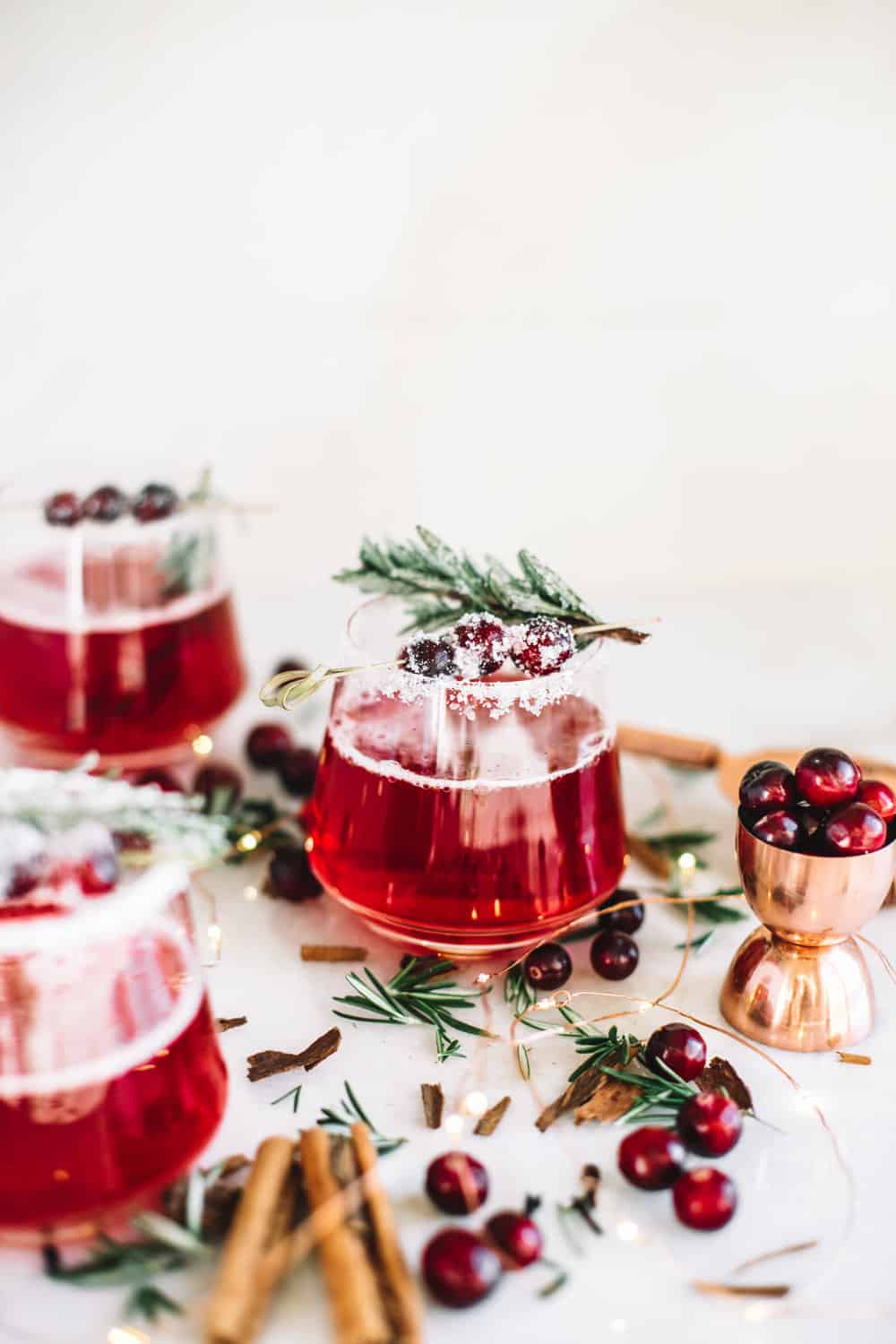 3 glasses of cranberry cocktails with cranberry and rosemary garnish