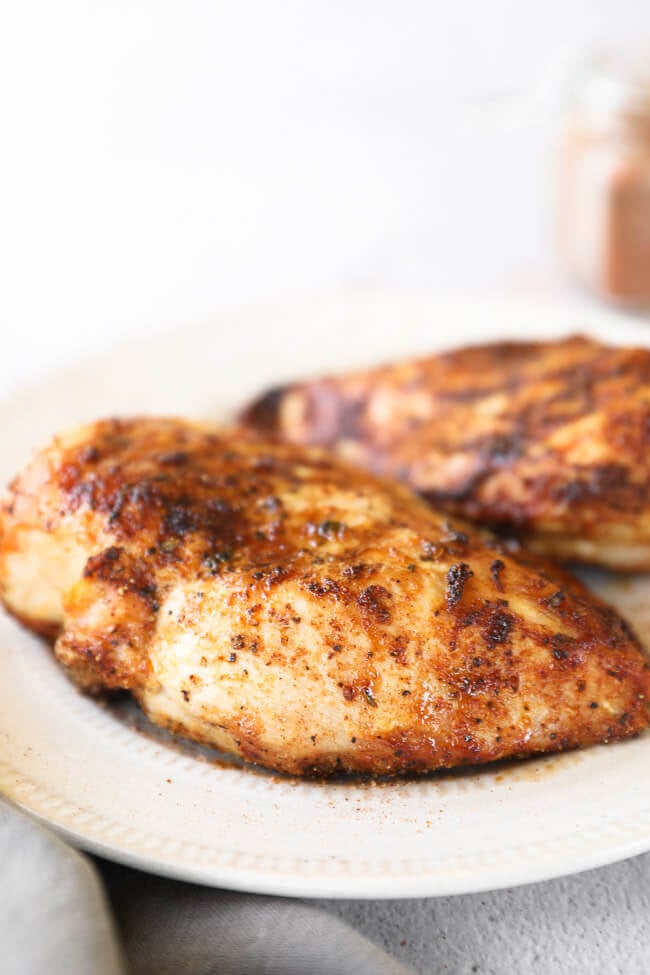Close up angle image of two chicken breasts on a plate.