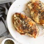 Cooked air fryer chicken breasts on a plate with seasonings