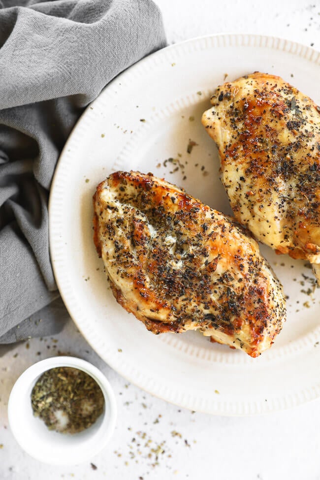 Cooked air fryer chicken breasts on a plate with seasonings