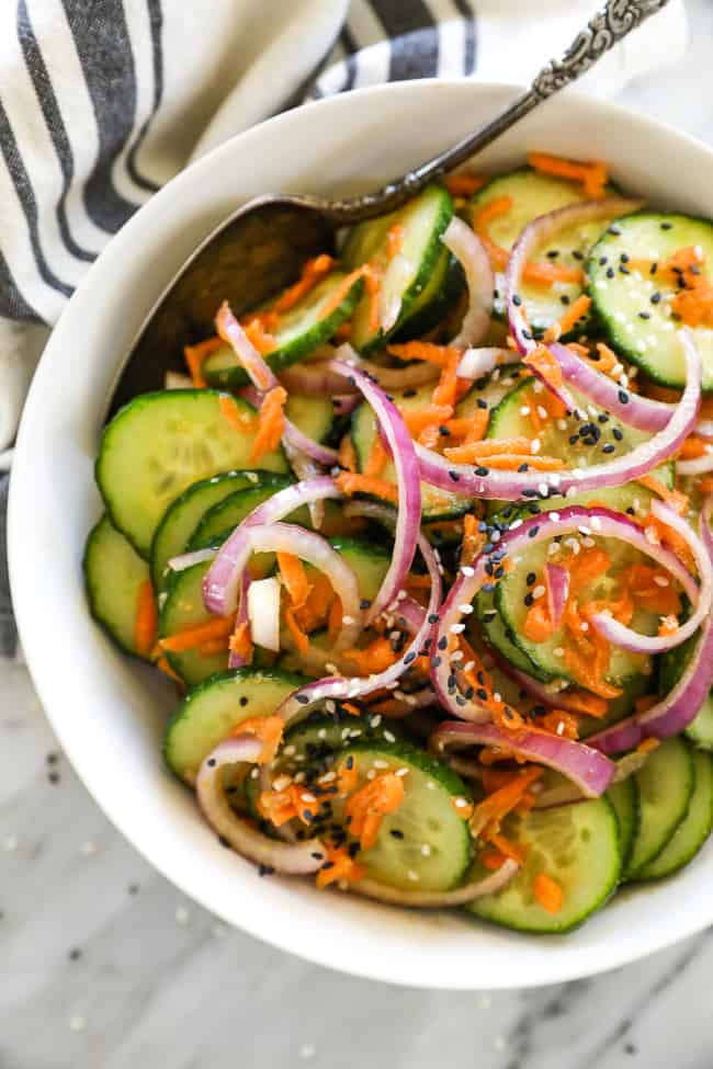 Asian cucumber salad in bowl with spoon vertical image