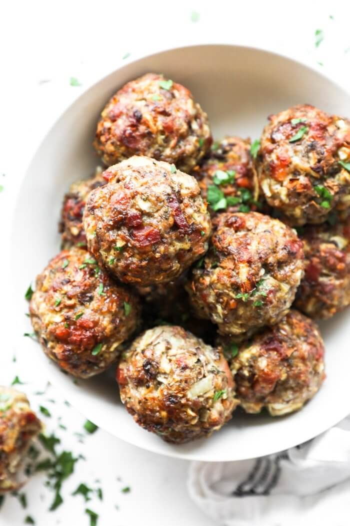 Overhead image of a bowl full of breakfast sausage meatballs. Topped with chopped parsley.