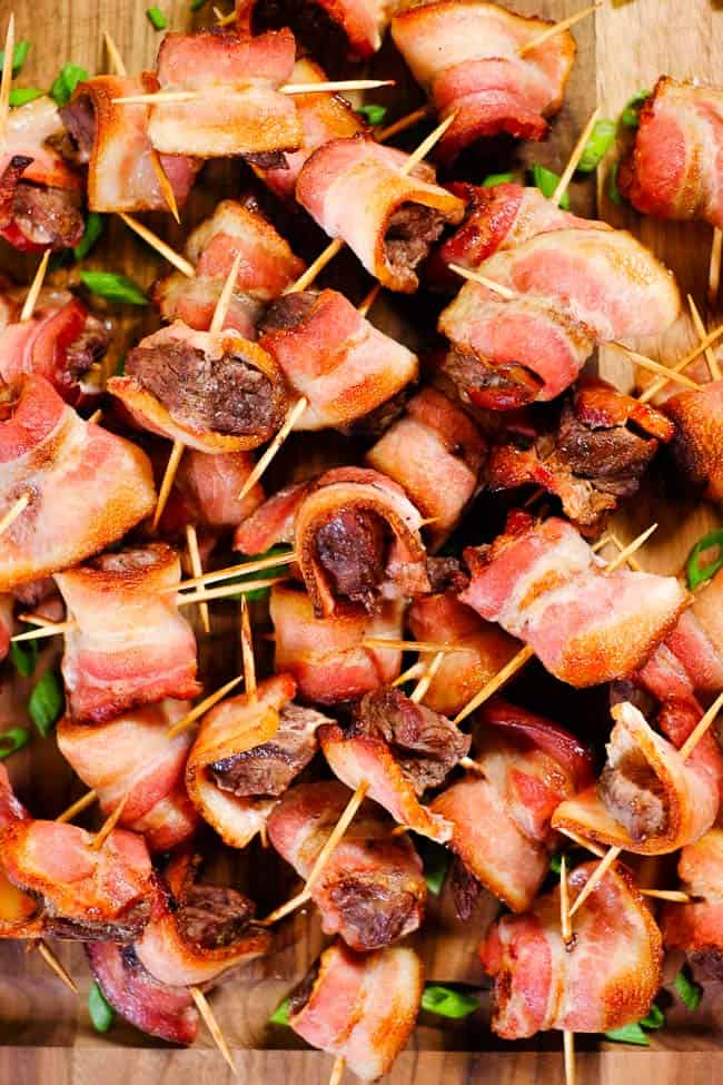 A pile of bacon wrapped steak bites speared with toothpicks 