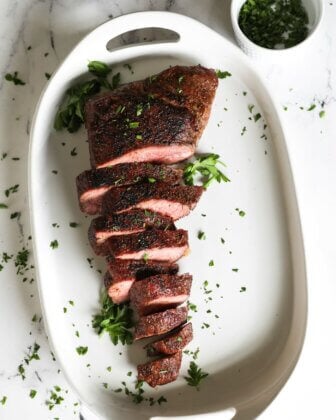 Overhead image of reverse sear smoked tri tip sliced on a platter with parsley garnish