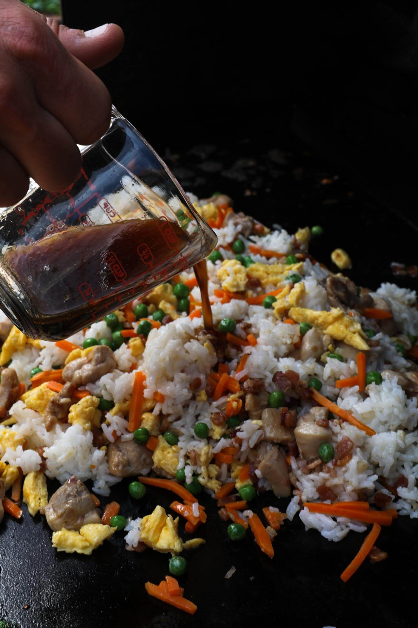 Pouring sauce over the fried rice mixture.