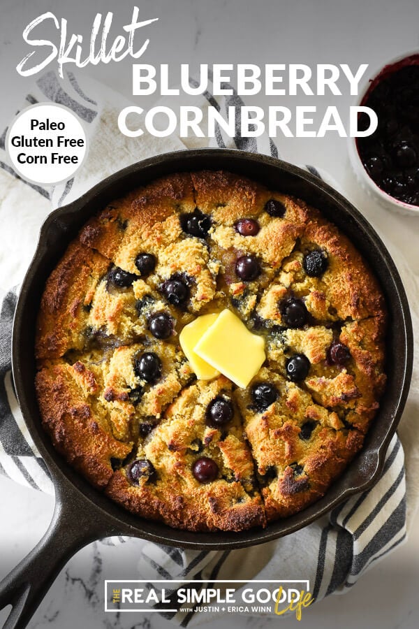 Vertical overhead image of blueberry cornbread in a skillet with extra blueberry sauce on the side. Text overlay at top of image. 