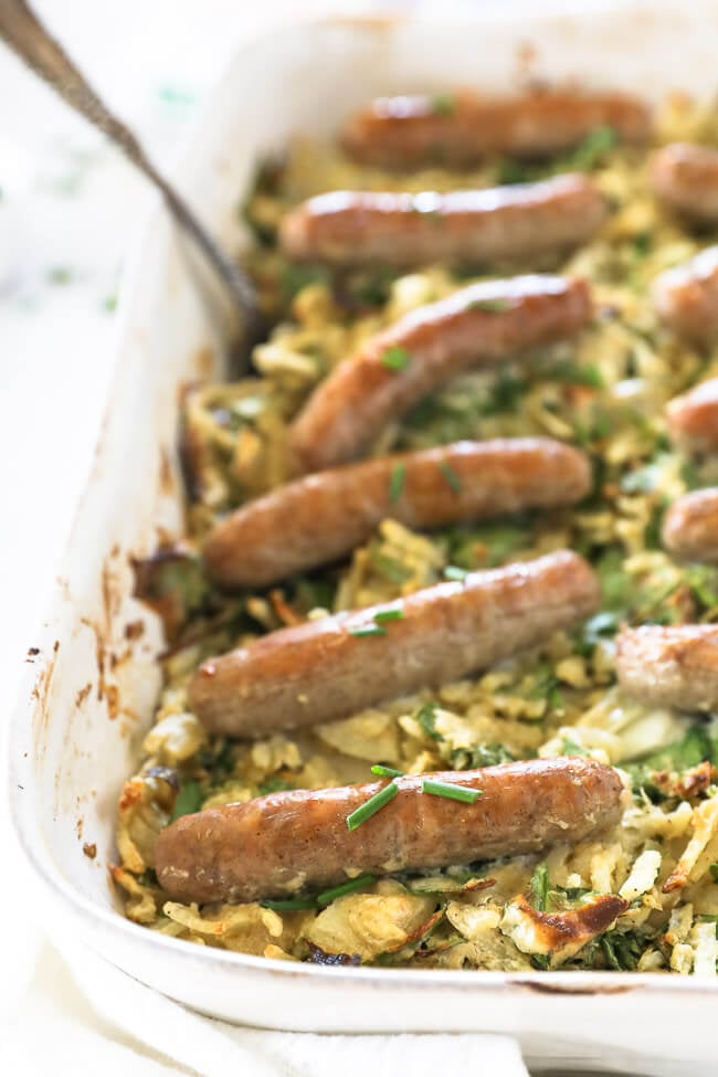 Vertical angled close up image of sausages topping a breakfast hashbrown casserole. 