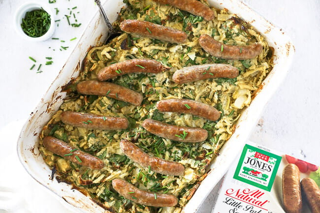 Horizontal overhead image of breakfast hashbrown casserole in a serving dish with a spoon and chopped chives on top. 