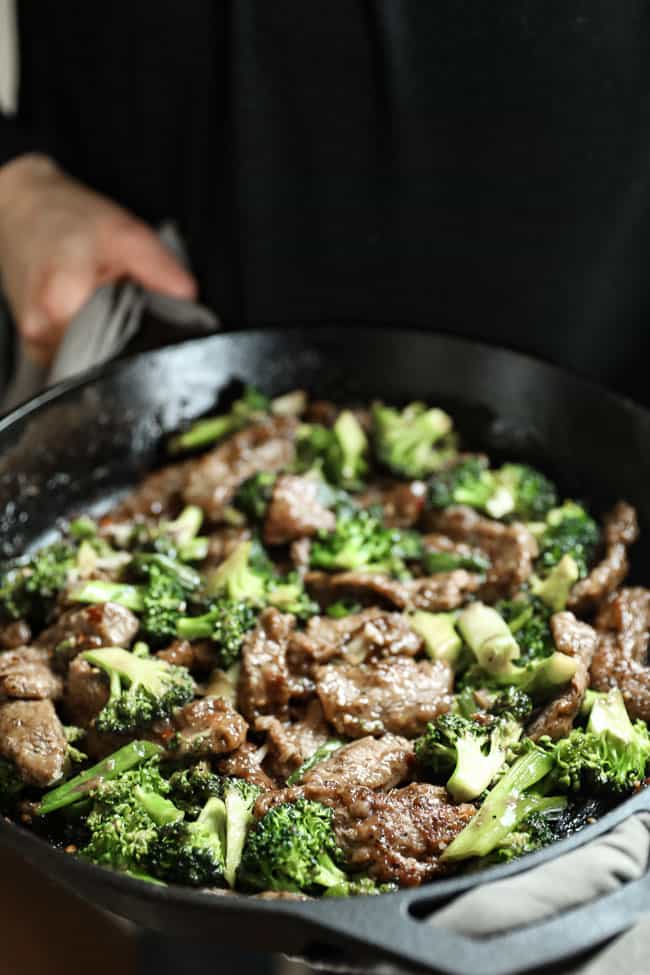 Holding a cast iron skillet with broccoli beef stir fry in it. 